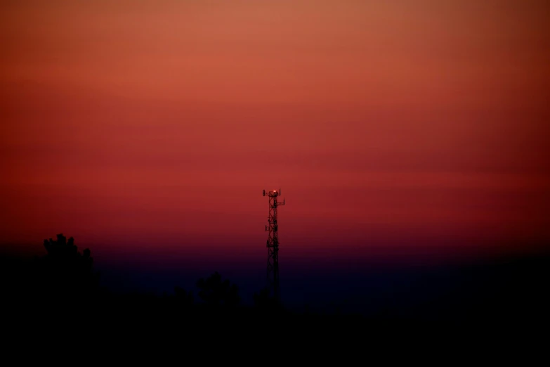 a tower is silhouetted against the bright red sky