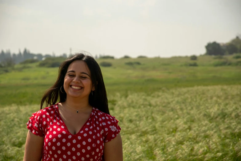 a beautiful young lady standing in front of green grass