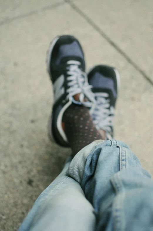 the feet of a person on a sidewalk with sneakers