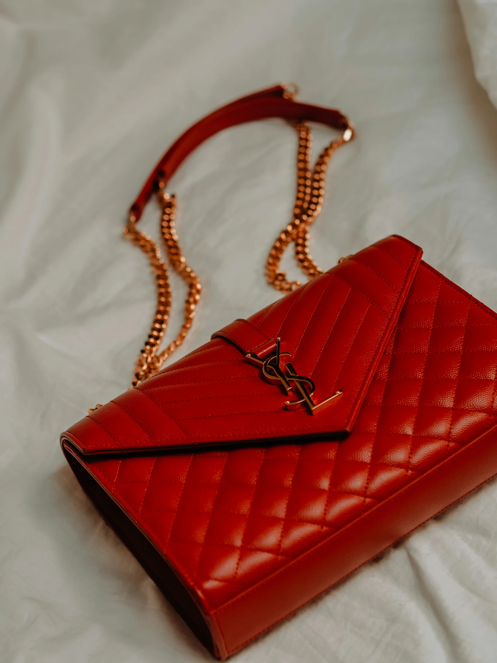 the red clutch is laying on a white sheet