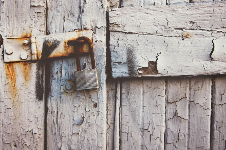 an old wooden door has a padlock on it