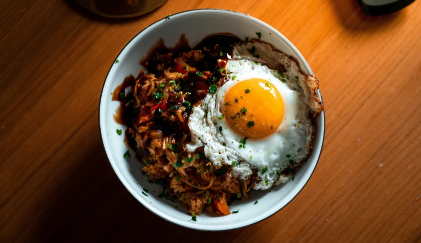 a bowl of fried eggs and a glass of beer on a table