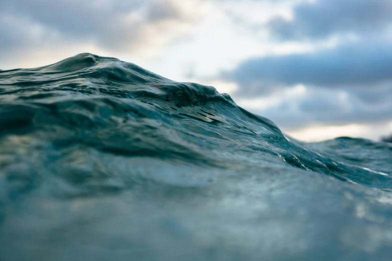 an ocean with grey clouds is seen in the sky