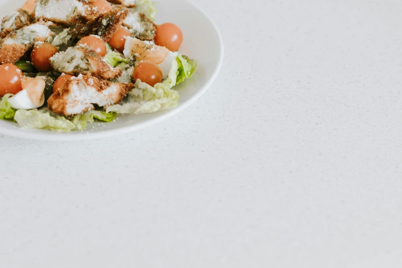 salad in white bowl on counter with a small spoon