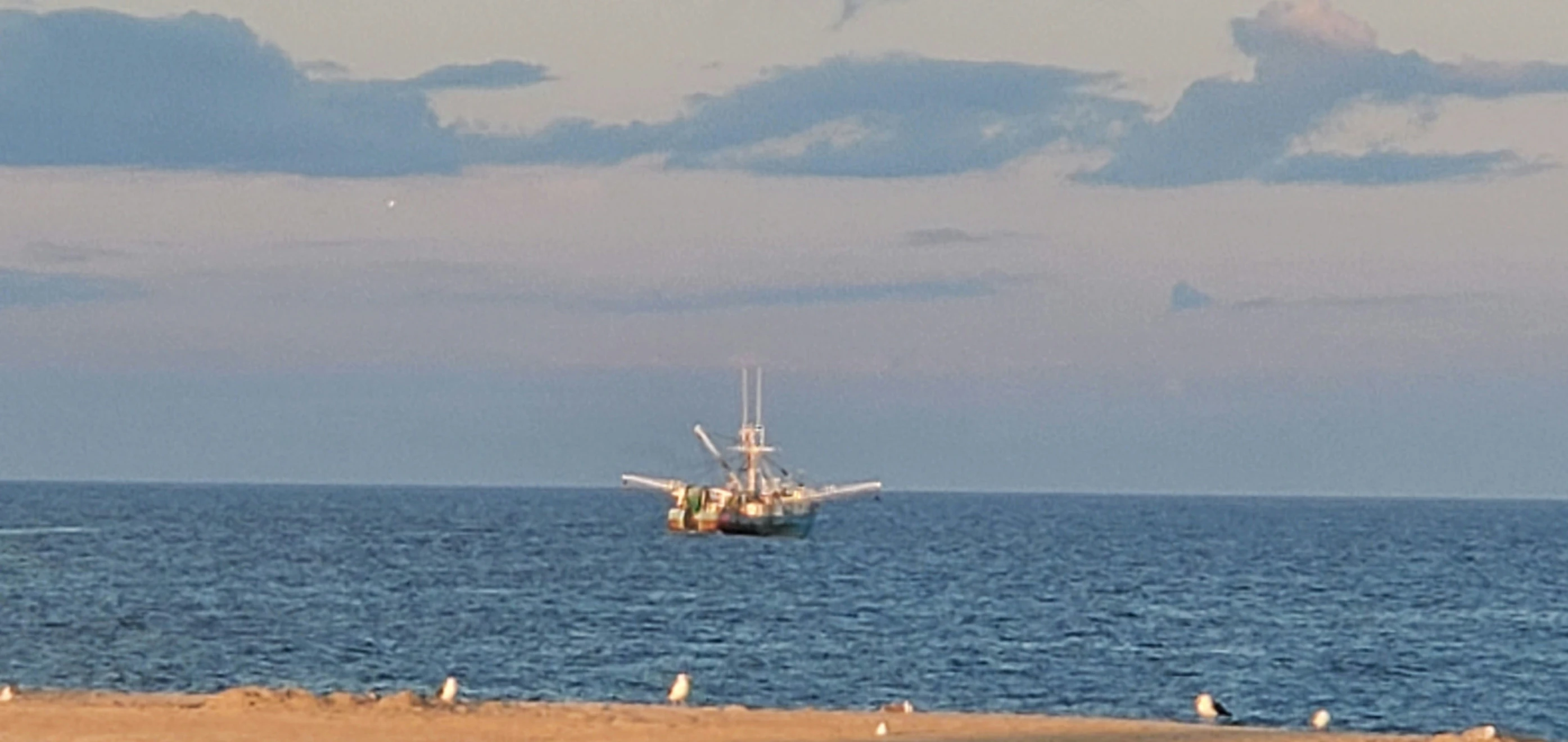 several boats sailing in the ocean under a blue sky