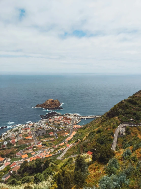 a town by the sea in the middle of a grassy hill