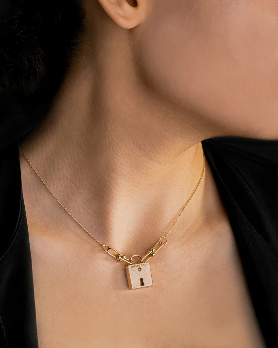 a woman with a square shaped lock necklace in gold