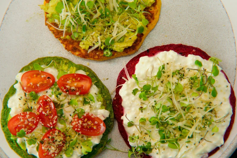 three small pizzas covered with different toppings on plates