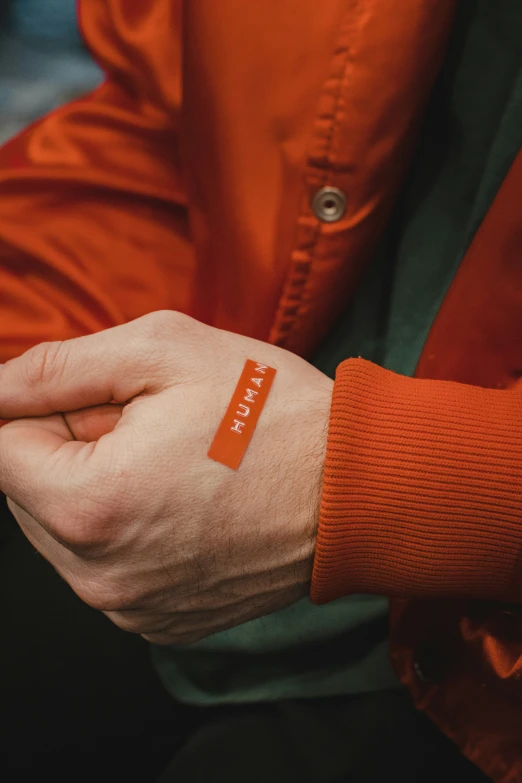 a person's hand with an orange logo on it