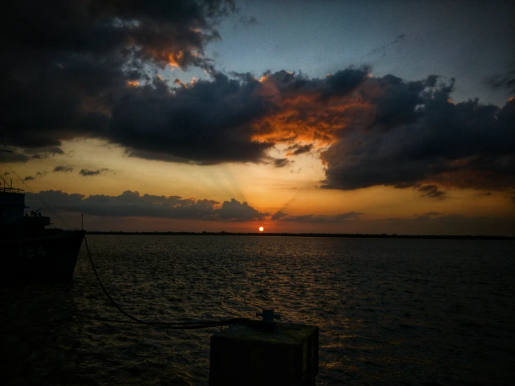 the sun sets behind clouds over the ocean