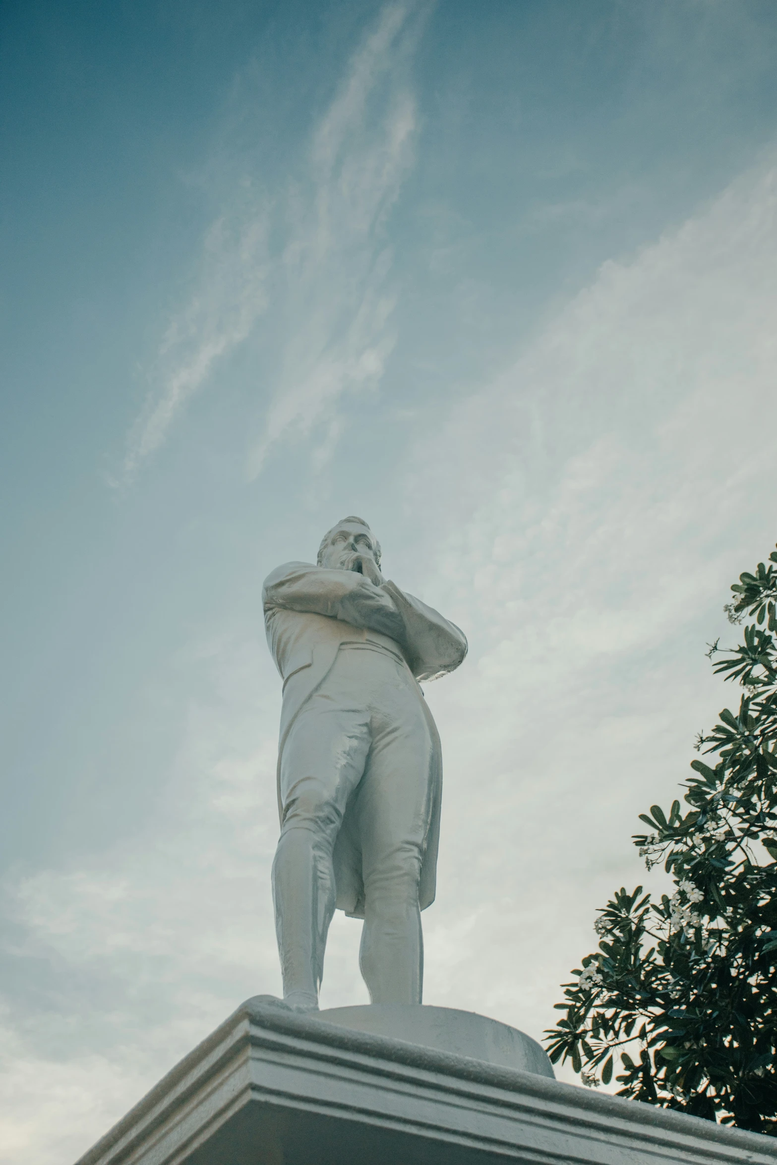 the large statue is next to a tree and clouds