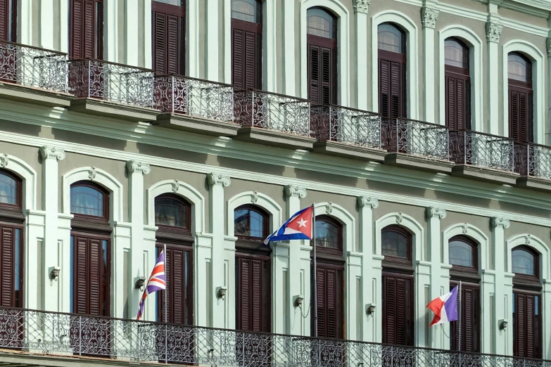 a building with balconies with three flags on each floor