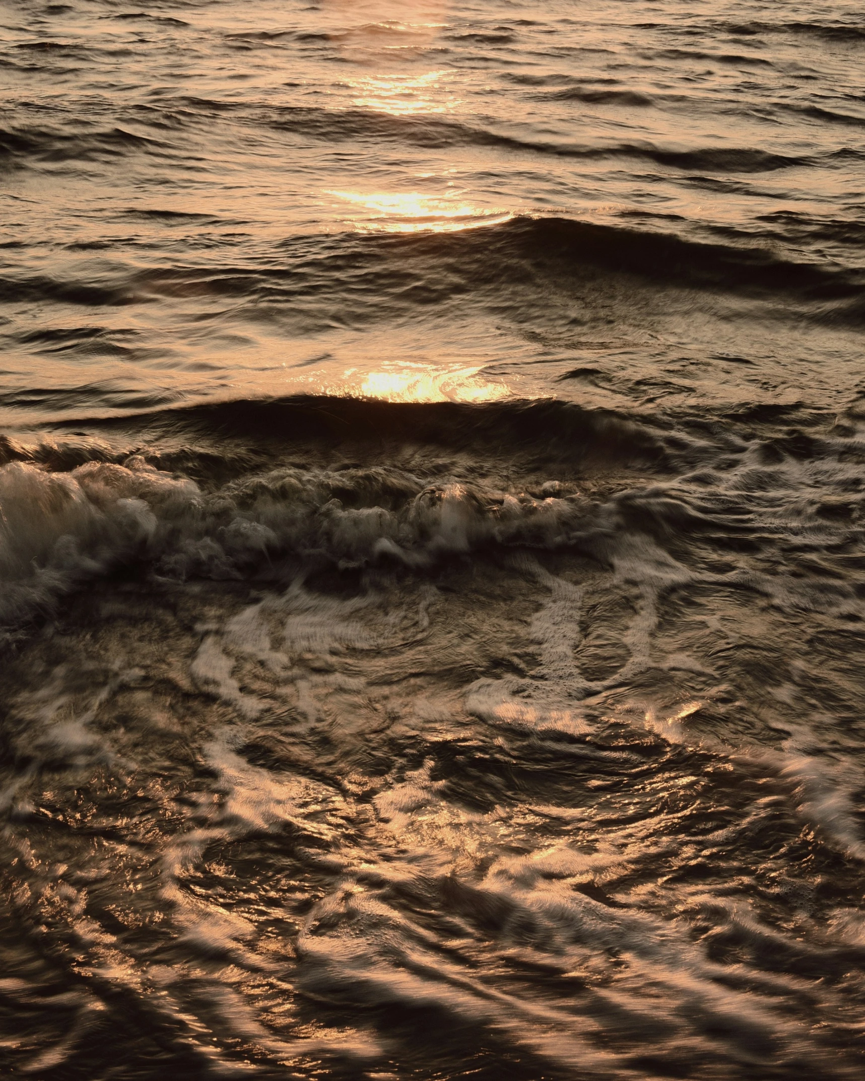 a sunset over the ocean with a wave and some foamy water