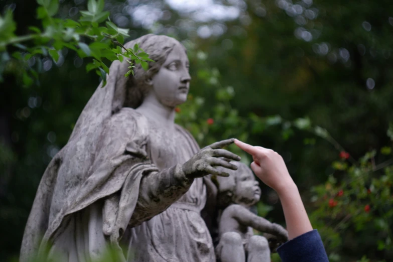 a girl touches the statue of an angel