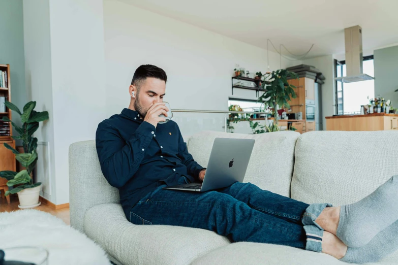 a man sitting on a couch using his laptop