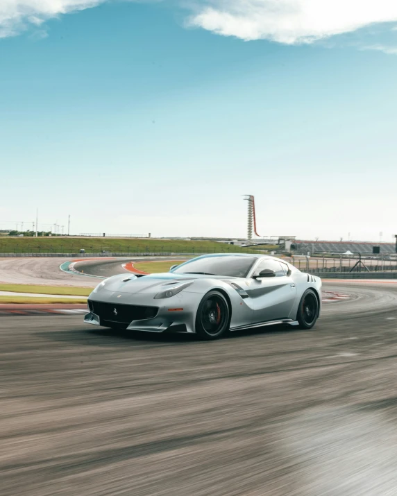 a silver sports car driving on a track