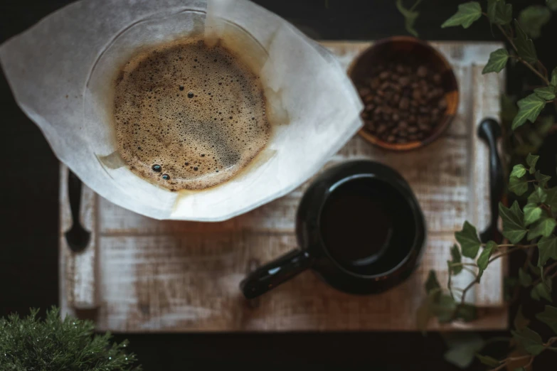 a white paper bag filled with coffee next to a cup