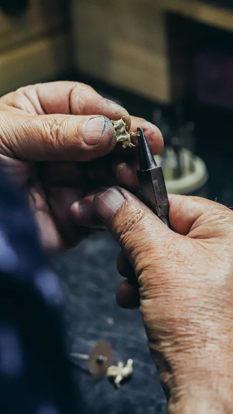 two hands holding a tiny wooden object while it looks like a cross