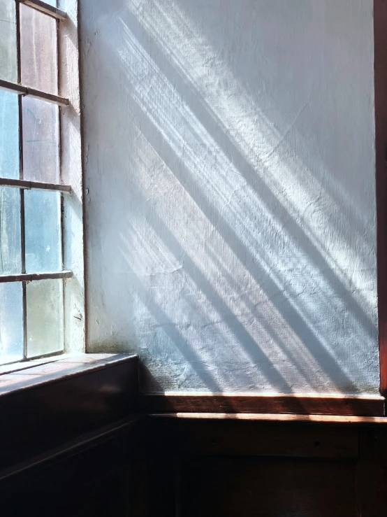 a wall and window with a shadow of the building across it