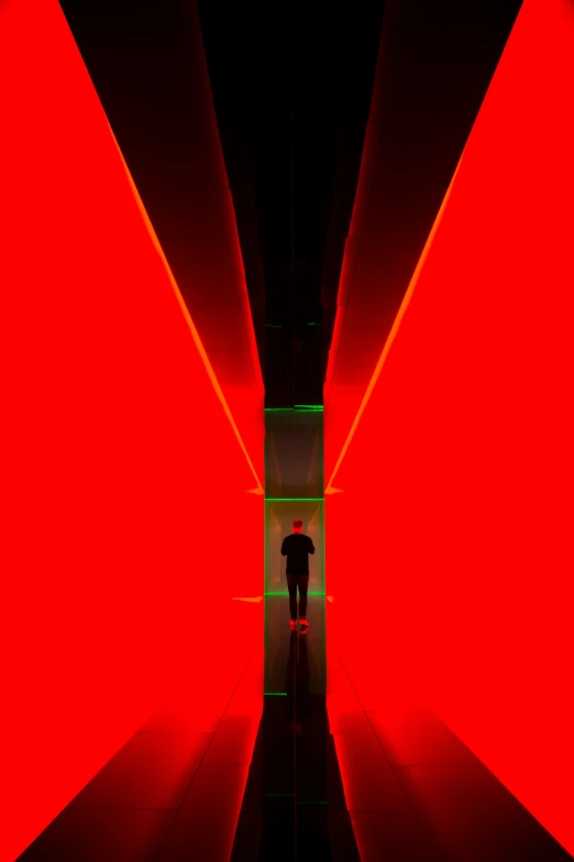 a man in the middle of a hallway that's red and green