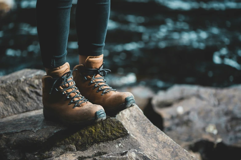 a person with brown boots standing on some rocks