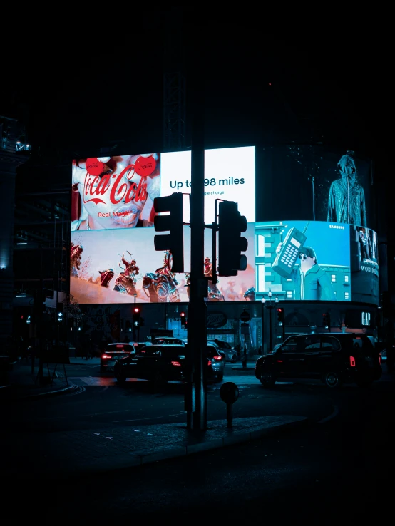 street lights, cars and billboards in an area at night