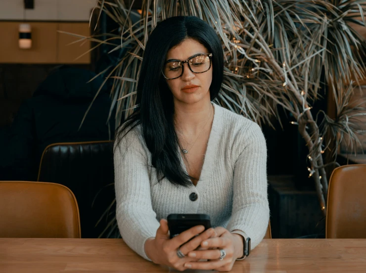 a girl holding a cell phone sitting at a table