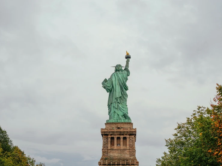 statue of liberty stands in front of the trees