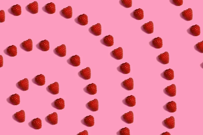 a large amount of strawberries are scattered over a pink background