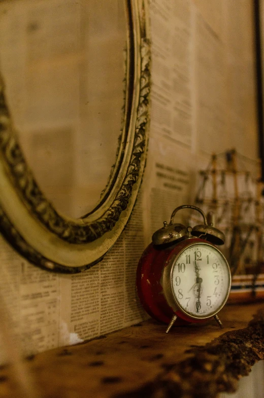 a red alarm clock sitting next to a mirror