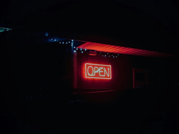 a lit neon open sign against dark background