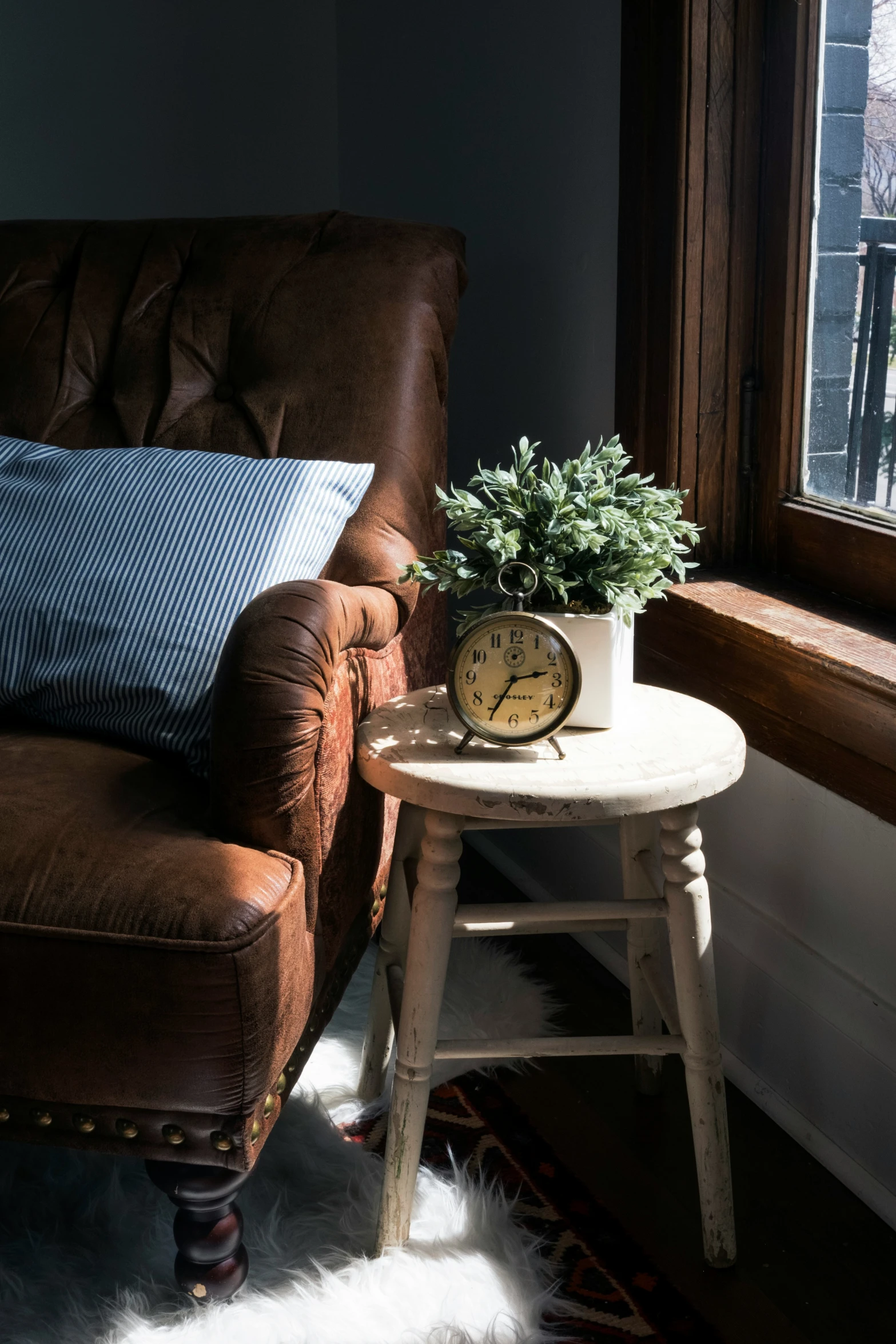 a small chair is next to an end table and clock