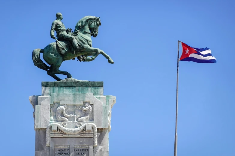 a statue with a horse that is near a flag pole