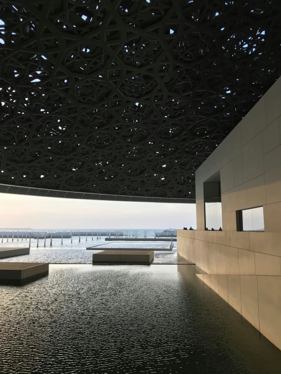 two benches sit under a structure by the water