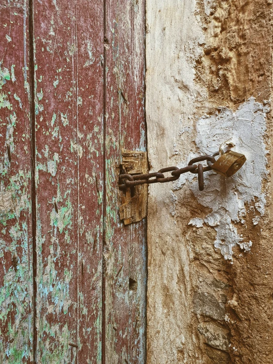 a rusted padlock on a red door with graffiti