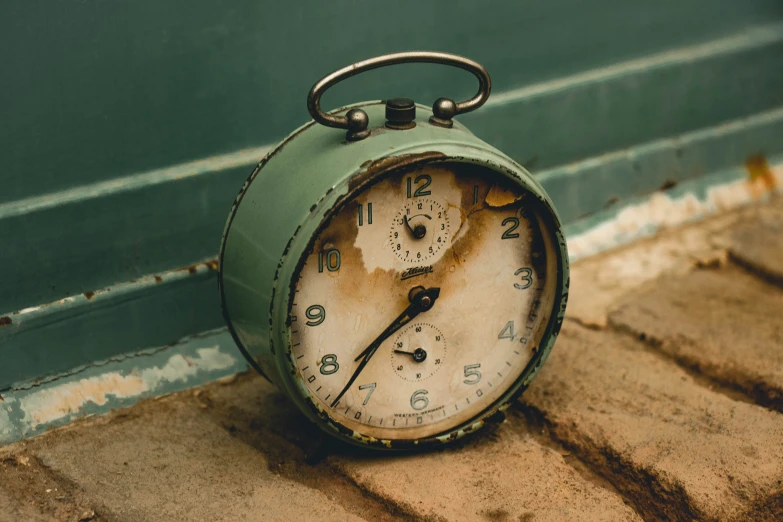 an old clock sitting on the side walk of a building