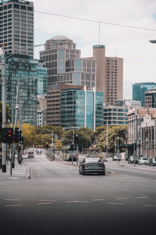 a car drives down an empty street near tall buildings