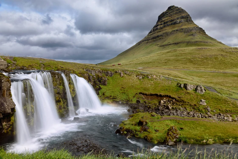 a tall mountain sitting next to a waterfall