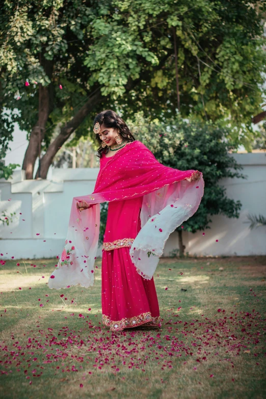 an indian woman dressed in a red and white sari dancing outside