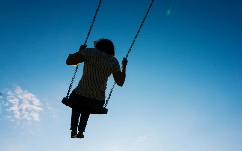 a woman sitting in a swing that has a rope between her legs