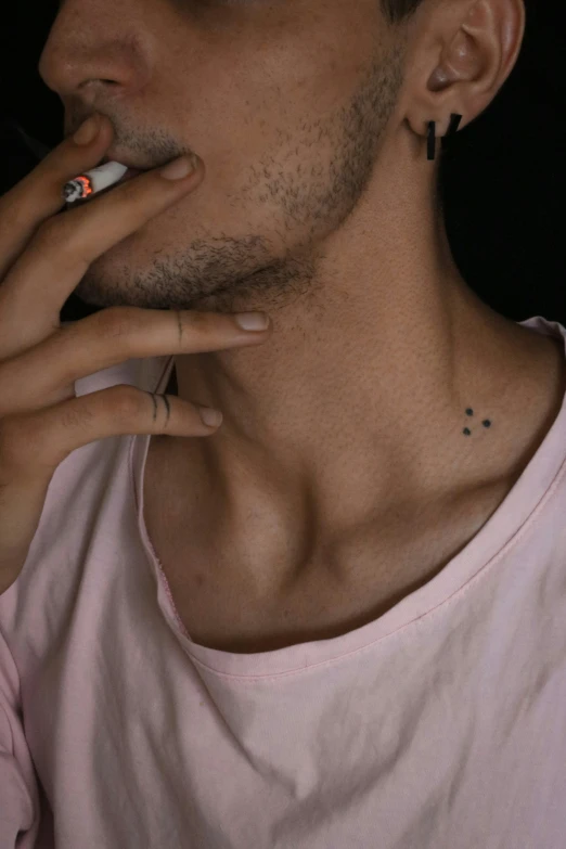 a man with tattoos on his left shoulder smoking a cigarette