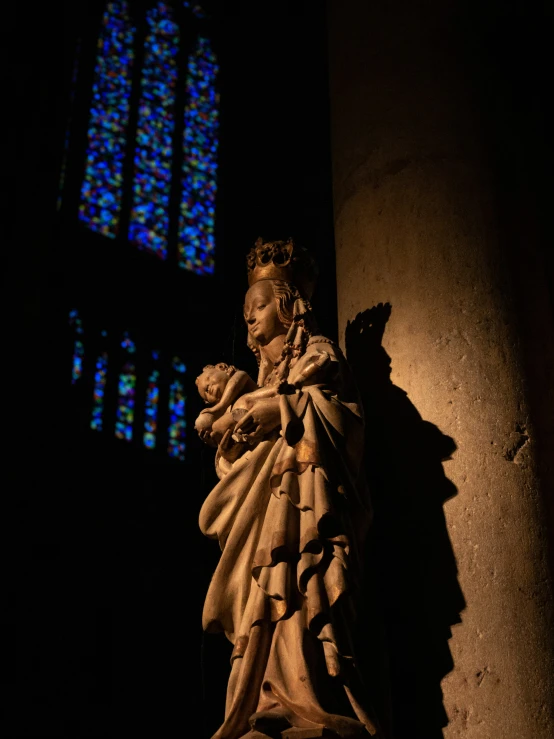 the statue of mary mary of loups against a stained glass window