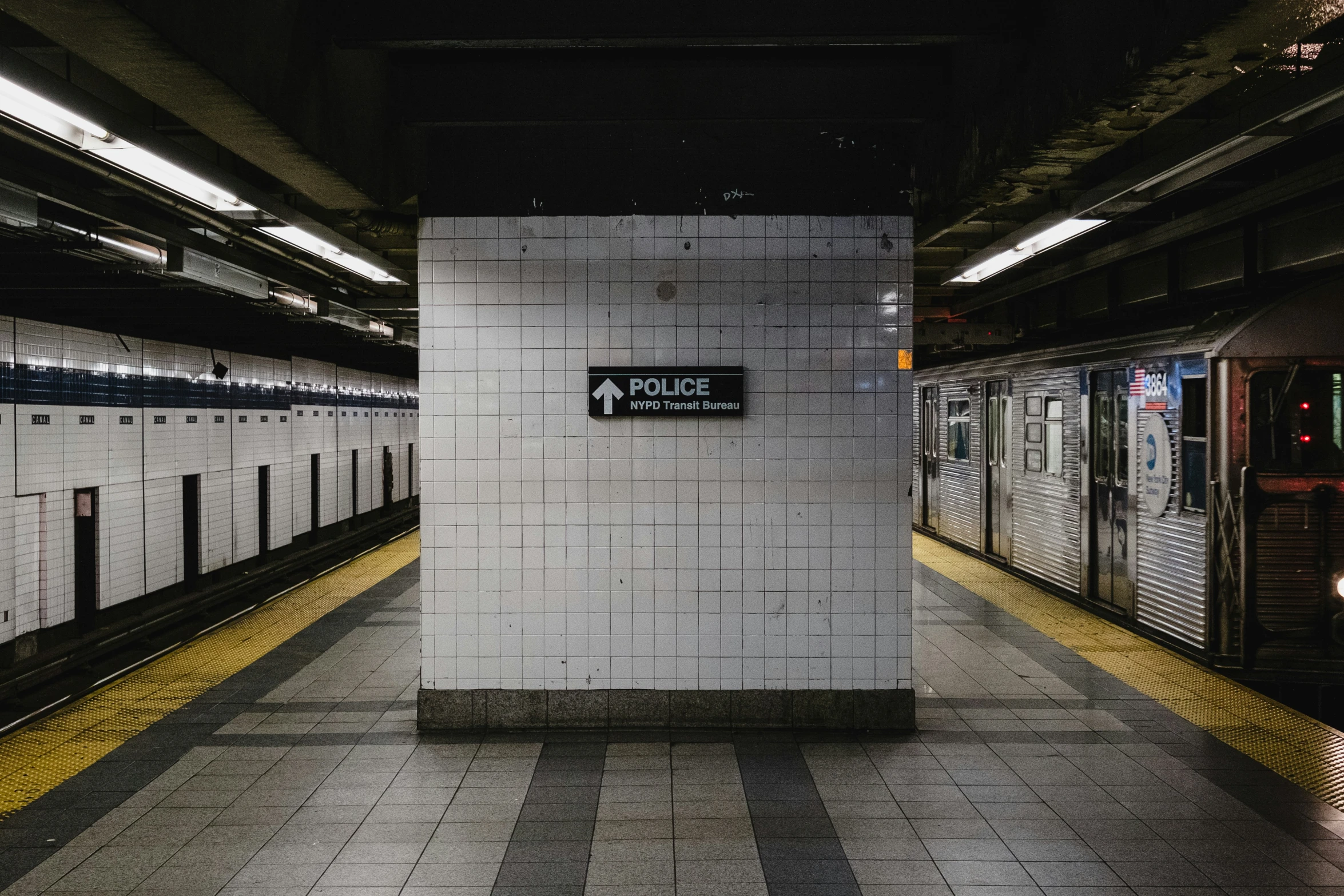 a subway station with tiled walls and yellow and white benches