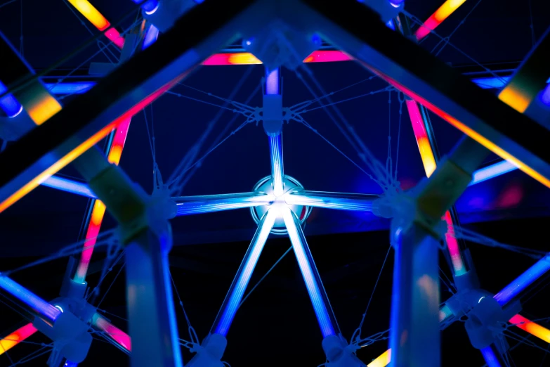 an illuminated ferris wheel at night with a blue sky in the background
