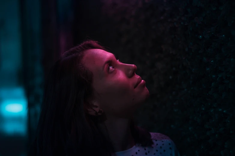 a woman stares upwards at a light