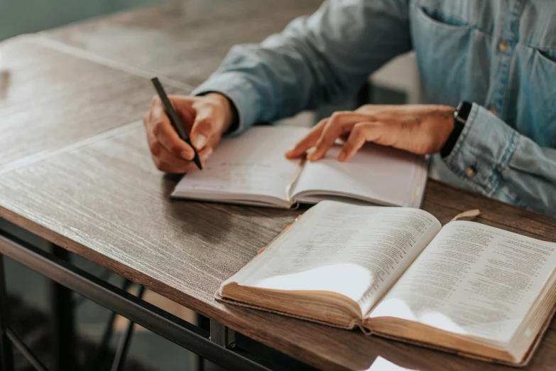 someone writing in an open book with a fountain pen