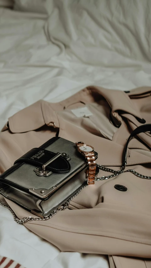 a purse and watch laying on a bed