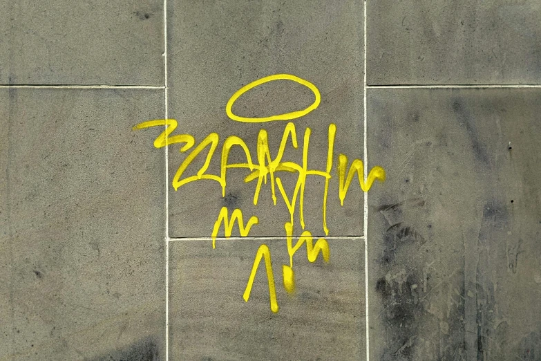 yellow graffiti that reads whaaas on a gray sidewalk