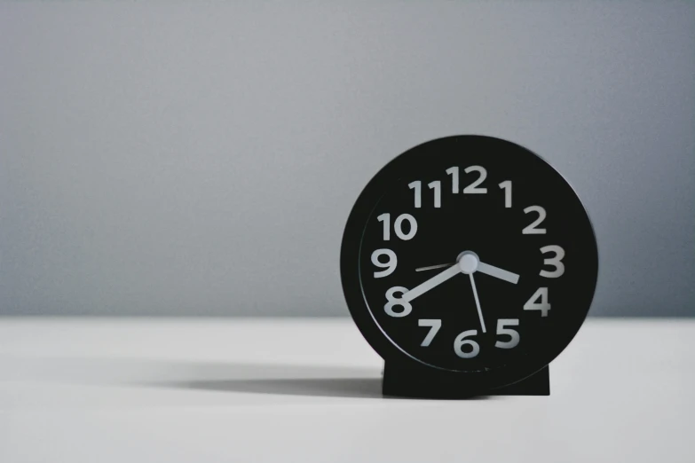 the black clock is sitting on the table