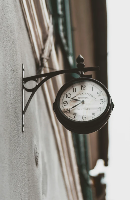 clock attached to the side of building wall